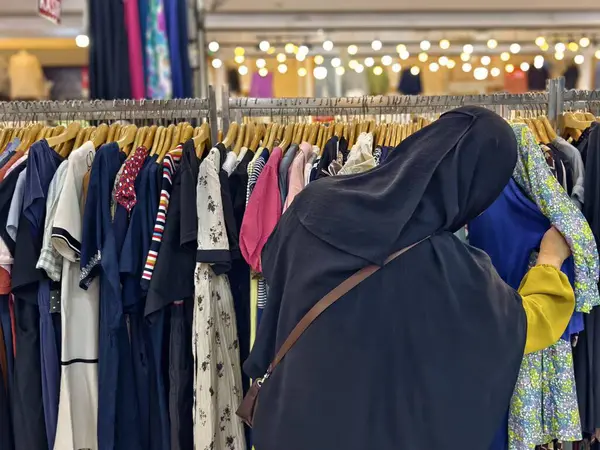 Bogor, Endonezya - 11 Mayıs 2025: Elbiseler ve gömlekler de dahil olmak üzere çeşitli kıyafetler, iyi aydınlatılmış geleneksel bir pazarda raflarda sergilendi. Yüksek kalite fotoğraf