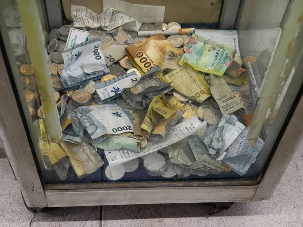 Bogor, Endonezya - 18 Mayıs 2025: Bağış kutusuna yığılmış bir yığın banknot, hayırseverliği ve cömertliği simgeliyor