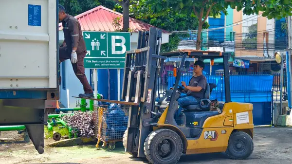 Bogor, Endonezya - 5 Haziran 2025: Forklift operatörü Endüstriyel Bölgede Büyük Beyaz Nakliye Konteynırını Güvenli Bir şekilde Boşaltıyor