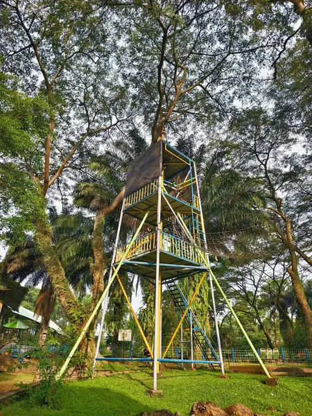 Parktaki yemyeşil ağaçların arasında renkli destekli çok katmanlı Uçan Tilki Fırlatma Kulesi. Yüksek kalite fotoğraf