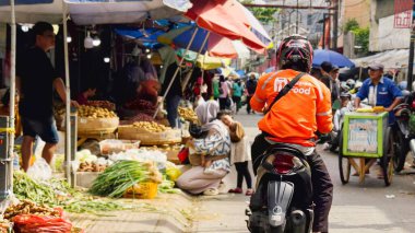 Bogor, Endonezya - 15 Haziran 2025: Gıda Teslimatçısı Motosikletle Kalabalık Geleneksel Market Caddesi 'nde Satıcılar ve Alışverişçiler ile Geziniyor. Yüksek kalite fotoğraf