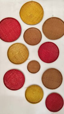 Kırmızı, sarı ve Doğal Kahverengi renklerle dekoratif örülmüş Rattan tabakları bir duvara yerleştirildi. Yüksek kalite fotoğraf