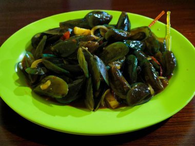 Lezzetli bir tabak kızarmış yeşil midye, popüler bir deniz ürünleri tabağı, canlı yeşil bir tabakta servis edilir..