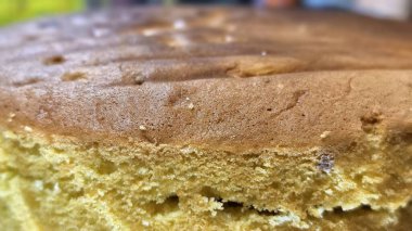 Yeni pişmiş bir kekin yakın çekimi altın-kahverengi kabuğunu ve nemli, gözenekli dokusunu gözler önüne seriyor..