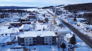Quebec 'teki Sayabec köyü üzerinde uçuş. Kilisenin kış manzarası ve karla kaplı diğer binalar birkaç arabanın seyahat ettiği bir yol ile kesişiyor..