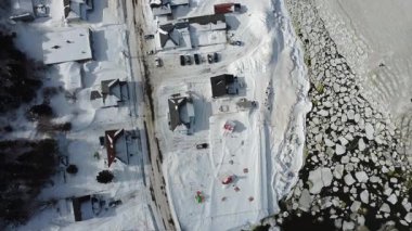 Panoramik dikey olarak küçük, tipik bir Gasp kıyı köyünün kışın kar ve buzla kaplı görüntüsü. Saint-Ulric-de-Matane, Quebec, Kanada.