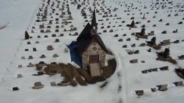 Sayabec 'teki J.C. Saindon Mezarlığı' nın toplu mezar kilisesi. Kardan bir battaniyenin altında cenaze anıtlarıyla çevrili küçük bir tuğla şapel. Quebec, Kanada, Kış 2025.