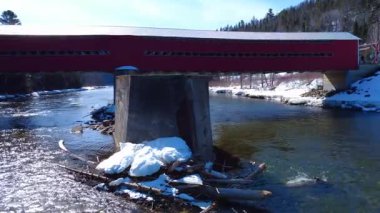 Merkezi sütun, tarihi bir köprünün ahşap yapısını ve beton yapısını nehrin yukarısındaki enkazlardan korumak için tutuyor. Matapedia Nehri, Routhierville Köprüsü, Quebec, Kanada, Kış 2025.