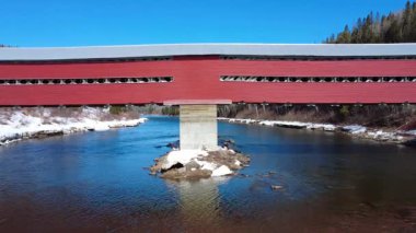 Routhierville Köprüsü 'nün ahşap yapısının altındaki merkez kirişe yakın geçit ve akıntıya karşı güçlendirilmiş beton kırıcı. Tarihi eser, simgesel somon nehri Matapedia Nehri 'ni kaplayan köprüyü kapsıyor. Quebec, Kanada, Kış 2025.