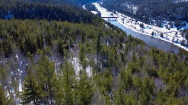 Routhierville Kapalı Köprüsü ve Matapedia Nehri 'nin karla kaplı bir dağ vadisinde akan panoramik hava manzarası. Quebec, Kanada, Kış 2025.