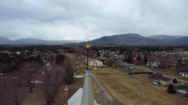 Çan kulesinin havadan görünüşü ve arkasında Appalachian Dağları olan Saint-Brigitte Kilisesi 'nin kırmızı tuğla cephesi. Maria, Quebec, Kanada, 2025.