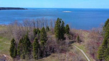 Ufukta gökyüzü ile birleşen mavi bir tuzlu su koyunda, uzak bir kayanın gökyüzü manzarası. St. Lawrence Nehri üzerinde, Quebec, Kanada, 2025.