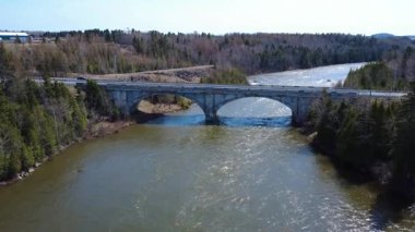Arthur-Bergeron Köprüsü 'nü filme alan ve Mitis Nehri' nin üzerindeki beton bir kemerin altında, Quebec, Kanada, 2025 'teki sel baskınıyla kahverengileşen bir dron tarafından çekilen video..