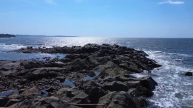 Güneşli mavi gökyüzünün altında parlak okyanus dalgalarıyla sakin kayalık sahil şeridi doğanın güzelliğini ve huzurunu yakalıyor. Deniz kıyılarının, deniz manzaralarının ve barışçıl çevrenin ideal tasviri. Metis-sur-Mer, Quebec, Kanada.