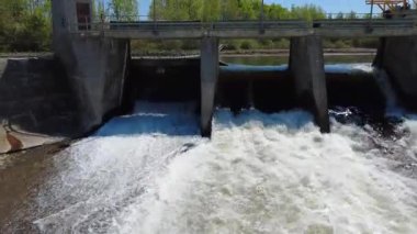 Küçük bir hidroelektrik baraj, yemyeşil ormanlarla çevrili su rezervuarının seviyesini dengelemek için taşkın kapılarından su salıyor. Mitis-1 Üretim İstasyonu, Fiyat, Quebec, Kanada.