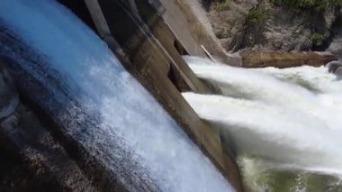 Enerji ve enerjiyi vurgulayarak bir çift baraj taşkınlığından güç kullanarak su fışkırıyor. Akış, su yönetimi ve hidroelektrik işlemlerin mekanik tasarımını göstermektedir. Mitis-2 Barajı, Price, Quebec, Kanada.