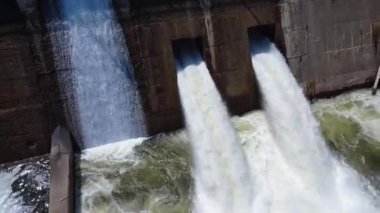 Hidroelektrik barajın güçlendirilmiş beton sızıntılarından izlenen bir çift dinamik su akışı, hidroelektrik enerjisi ve altyapıyı ön plana çıkaran bir havzaya boşalıyor..
