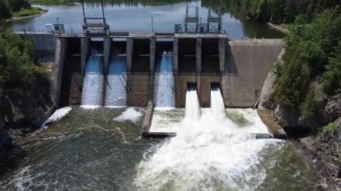 Çağlayarak akan su ve tam akış yardım kapılarına sahip bir hidroelektrik barajı, endüstriyel tasarım ve bereketli orman ortamının birleşimi, sürdürülebilir yenilenebilir enerji üretimi ve huzurlu doğal güzelliği sergiliyor.. 