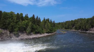 Metis Nehri üzerinde bir manzara, ünlü bir somon sporu balıkçılık nehri ve açık mavi gökyüzünün altındaki yemyeşil bankalar. Price, Quebec, Kanada.