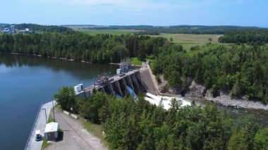 Hidroelektrik barajın üzerindeki hava manzarası ve boşaltım kapılarına açılan yol, beton duvarın üzerinden akan güçlü su püskürtüleri ve şelaleler yaratıyor. Mitis-2, Price, Quebec, Kanada.