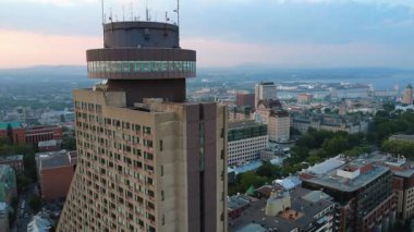 İnsanlar Loews Le Concorde Oteli 'nin tepesinde, Quebec City' nin ve çevresindeki binaların üzerinde yer alan restoranda oturuyorlar ve misafirlere St. Lawrence Nehri 'nin panoramik manzarasını sunuyorlar..