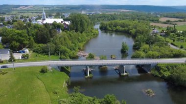 Onsime-Gagnon köprüsünün altından geçene kadar Fiyat belediyesinin havadan görüntüsü La Mitis somon balıkçılığı nehrini birkaç arabayla geçti. Fiyat Şehri, Quebec, Kanada, 2025.
