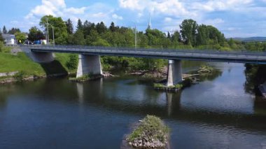 Bulutlu bir gökyüzünün altında, ormanın kenarındaki beton sütunların arasından geçen bir dron tarafından çekilen video..