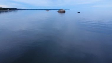Huzurlu mavi suların üzerinden uçtuğu kıyı manzarası martılar, yüzeyden çıkan kayalar ve bulutlu bir gökyüzü, rahatlama ve ilham için mükemmel bir deniz manzarası yaratıyor..