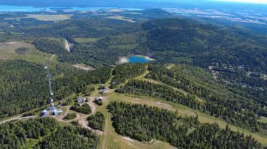 Verdant Matapedia Vadisi 'nin panoramik hava manzarası ve zirvesindeki telekomünikasyon anten kulesiyle Mont Val d' Irne kayak merkezinin tepesinden gölü. Quebec, Kanada, 2025.