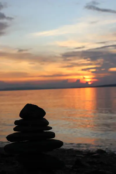 Kayaların, gökyüzünün, deniz suyunun ve gün batımında sahilin resimleri.