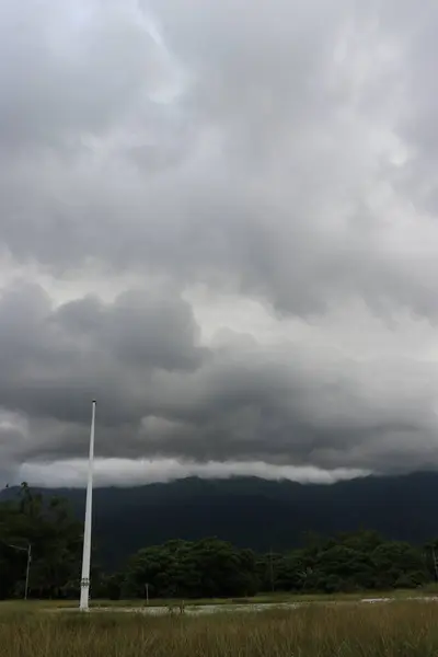 Sabahları ağaçlar, bulutlar ve sakin gökyüzü görünen dağların estetik görüntüsü.