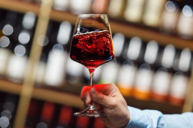 Şarap uzmanı kırmızı şarap kadehinin kıvrımlarını ve aromasını inceledi. Bulanık ahşap mahzende bedava fotokopi alanı var..