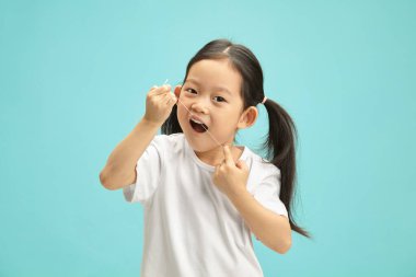 Diş ipi kullanan kadın çocuk, mavi arka planda izole edilmiş portre ve bedava fotokopi alanı. Çocuk ağız temizliği konsepti. Çocuk diş bakımı. Asyalı etnik kökenli küçük kız oral seks yapıyor.