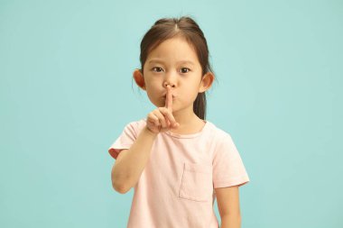 Sessizlik ve sessizlik isteyen, ağzı önünde el kol hareketi yapan, sessiz kalan ya da mavi izole edilmiş arka plana karşı bir sır saklayan ve bedava fotokopi alanı olan küçük tatlı bir çocuk..