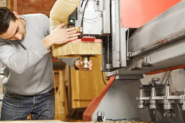 stock image Man sets the cutter in the CNC machine. Device with numerical control. Woodworking industry.