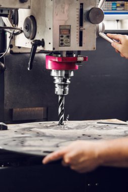 Dikey matkapla metal parçalarında delikler açılır. Metal sondaj makinesine yakın çekim. Alt cıvata deliğini deliyorum. Yüksek kalite fotoğraf