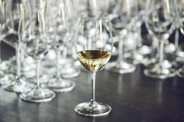 Masadaki beyaz şarap kadehleri, arka plandaki boş bokalara karşı. Alkolik içecekler tadıyor. Sommelier degustation okulu. 