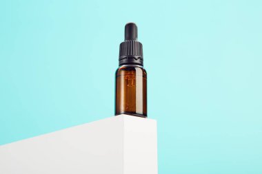 Kimyasal sıvı, parfüm, yağ ve serum için açılan cam damlaları mavi arka planda beyaz dikdörtgen şeklinde. Spa, masaj, cilt bakım ürünleri kataloğu için kahverengi şişe.