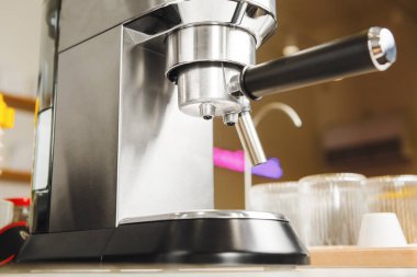 Küçük sıkıştırılmış gri kahve makinesi mutfak tezgahının üzerinde duruyor. Metalik espresso filtresi takılı ve kullanıma hazır.. 