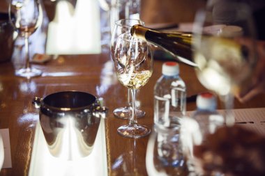 Garsonun şarap şoklama sırasında bardağa beyaz şarap dökerken yakın plan fotoğrafı. Alkollü içecekler için şarap garsonu ve personel eğitimi. Profesyonel iş sertifikası sınavı. Şarap.