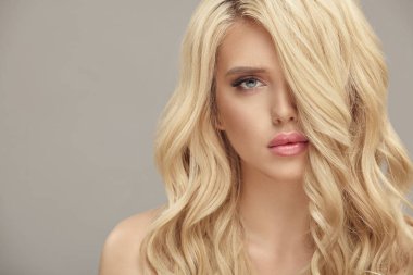 Güzel sarı saçları ve bej arka planda izole edilmiş çok renkli makyajı olan güzel bir kadın.