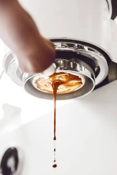 stock image Close-up photo of thick stream of espresso pouring from bottomless portafilter, showcasing beautiful crema against light backdrop. Basic rules for making high-quality espresso. Coffee preparation