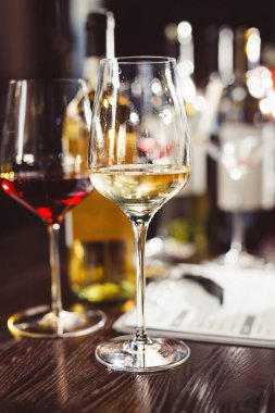 Şişeler, kök bardaklar boş ve kırmızı, beyaz içecekler, kalem, kağıtlar modern restoranda ahşap masanın üzerinde, bar, içki, şarap, içki. Şarap tatma, tezgahta değerlendirme aksesuarları..