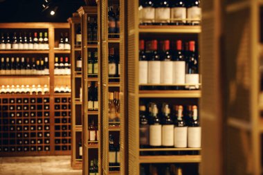 Şarap mahzeninde raflar çeşitli şişe pozisyonlarıyla doluydu. İçki dükkanında bir sürü şarap var. Yüksek şarap rafları ve büyük bir mağazanın mahzeninde bir şişe elit alkol..