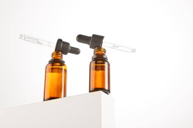 Kehribar düşürücü şişeleri, yüz sıvısı için kolajen, peptit, vitamin içeren kozmetik maddeler. Kahverengi açık şişe boyunlarında serumlu iki siyah pipet var. Kapatın. Katalog şablonu.