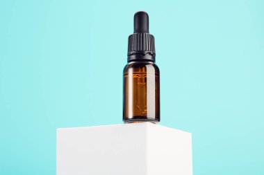 Kimyasal sıvı, parfüm, yağ ve serum için cam damlalar mavi arka planda beyaz dikdörtgen şeklinde. Spa, masaj, cilt bakım ürünleri kataloğu için kahverengi şişe..