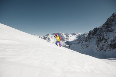 Active female person rising up on snow-covered mountain with speed and skill, navigating the climbs effortlessly. clipart