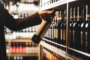 Sommelier, şarap şişesi etiketini yakından inceliyor. Raftan seçtiği şarap şişelerinin şarap mahzenindeki çeşitli şişelerle dolu olduğunu ve şarap mahzeninin kalitesini ve kökeninin kriterlerini karşıladığından emin olmak için..