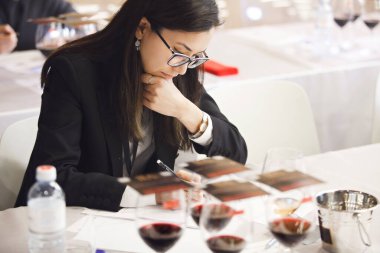 Thoughtful woman studying wine characteristics, making notes during blind tasting sommelier training session. Sommelier courses for beginners and experienced. Training and examination for get clipart