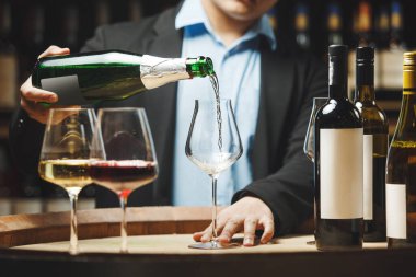 Meçhul şarap garsonu şarap mahzenindeki ahşap fıçının üzerine beyaz şarap dolduruyor..